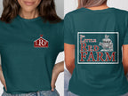 A woman wearing a dark teal t-shirt with a small barn logo on the front and farm animals stacked on the back.