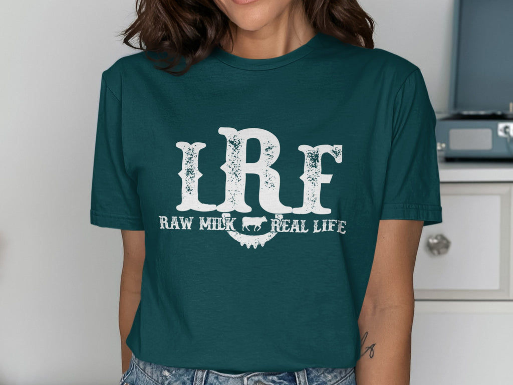Teal t-shirt with white distressed text "LRF RAW MILK REAL LIFE" and a cow illustration.